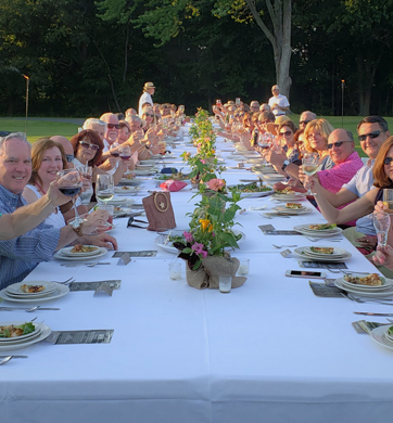 Members gathering for a meal at a social event outside at Wolferts Roost in Albany, New York.